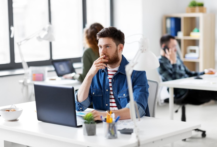 Foto kreativer mann mit laptop, der im büro arbeitet
