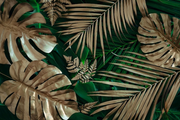 Kreativer Naturhintergrund Gold und grüne tropische Monstera und Palmblätter Minimale Sommerabstraktion