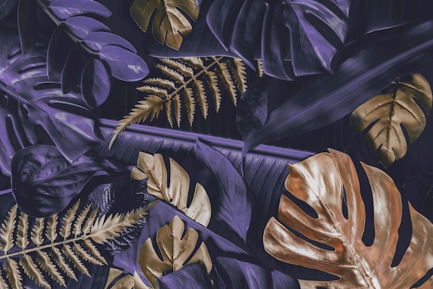 Kreativer Naturhintergrund Gold und lila tropische Monstera und Palmblätter