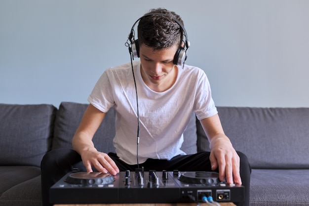 Kreativer Teenager in Kopfhörern mit Mixer-Unterhaltungs-DJ-Station, Teenager, der sich für Musik, Hobbys und Freizeit des jungen Mannes interessiert