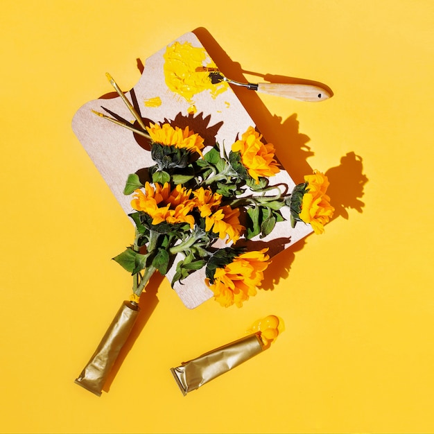 Kreatives Flatlay mit Künstlerbedarf und Sonnenblumen auf Gelb