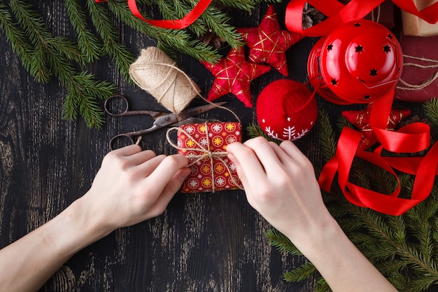 Kreatives Hobby. Hände wickeln Weihnachtsfeiertag handgemachtes Geschenk in Bastelpapier mit Schnurband