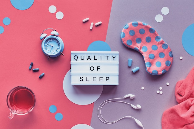 Kreatives Konzept des gesunden Nachtschlafes. Schlafmaske, blauer Minzalarm, Kopfhörer und Ohrstöpsel.