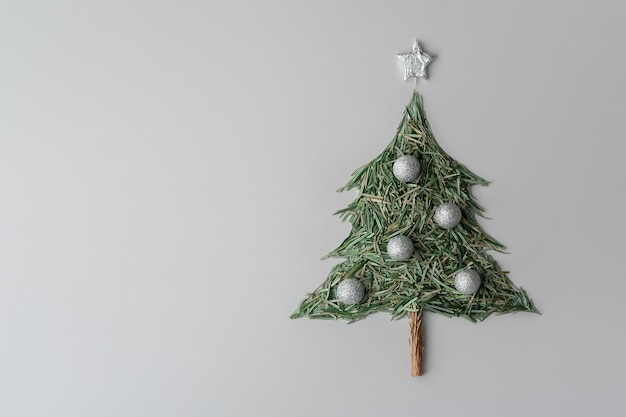 Kreatives Konzept von Weihnachten und Neujahr Weihnachtsbaum aus Weihnachtsbaumnadeln auf grauem Hintergrund mit Kopierraum