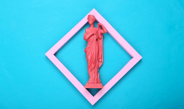 Kreatives Layout Rosa antike griechische Göttinnenstatue im Rahmen auf blauem Hintergrund Minimalismus Flache Ansicht von oben