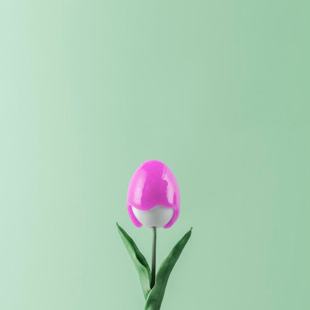 Foto kreatives osternkonzept tulpe mit einer knospe in form eines ostereies mit rosa farbe, die nach unten fließt