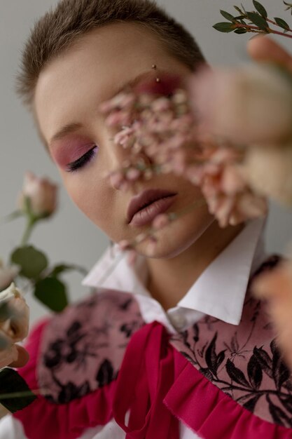 Kreatives Shooting in einem Fotostudio Mädchen mit kurzem Haarschnitt mit hellem Make-up und Blumen