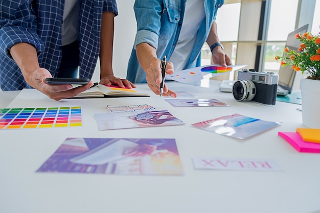 Kreatives Startteam des asiatischen Werbungsdesigners, das Ideen im Büro bespricht.