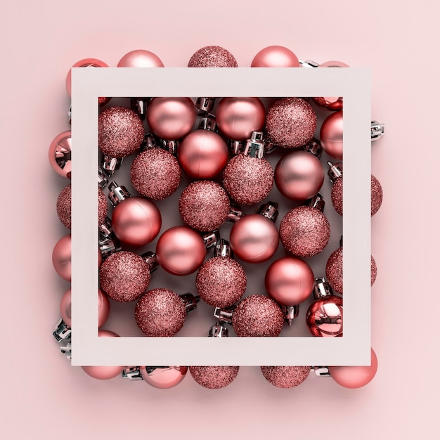 Foto kreatives weihnachtsmockup mit weißem quadratischen rahmen und rosa weihnachtenbaumkugeln auf rosa hintergrund