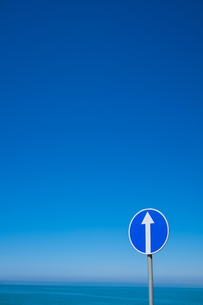Kreisverkehrsschild mit weißem Pfeil auf Hintergrund des blauen Himmels