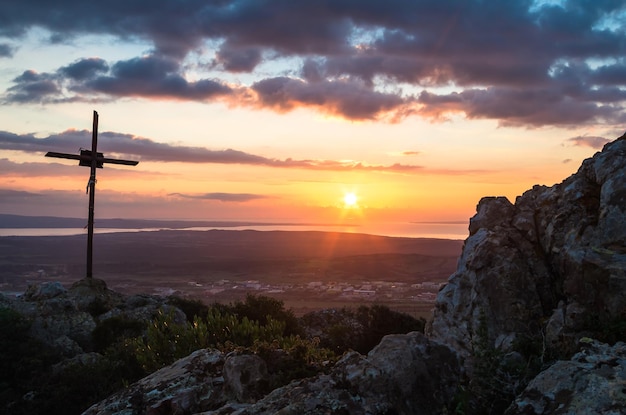 Kreuz auf dem Berg gegen bewölkten Himmel bei Sonnenuntergang
