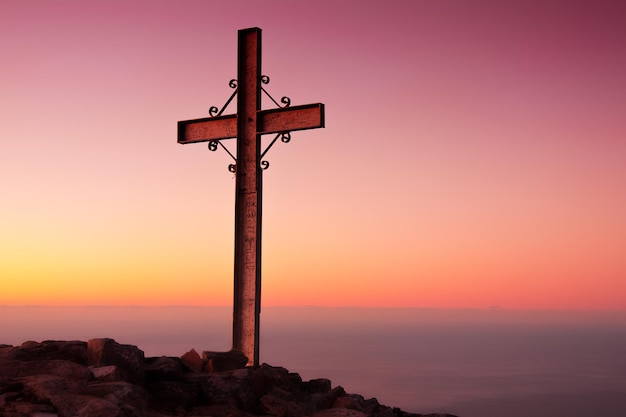 Kreuz gegen den klaren Himmel beim Sonnenuntergang