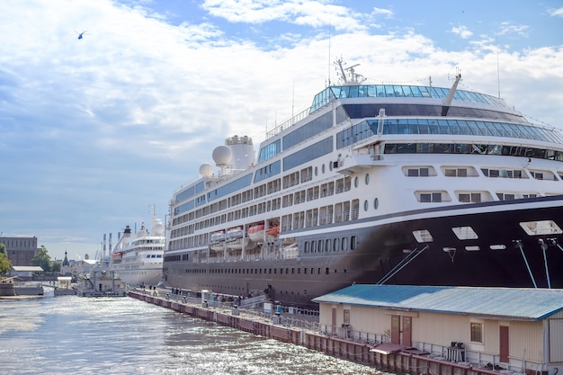 Kreuzfahrtpassagierschiff am Pier am sonnigen Tag. Kreuzfahrtschiff verankert im Hafen des Hafens. Seehafen. Seekreuzfahrt auf dem Schiff. Wassertourismus. Reisen in Europa. weißes Schiff steht in der Hafenstadt