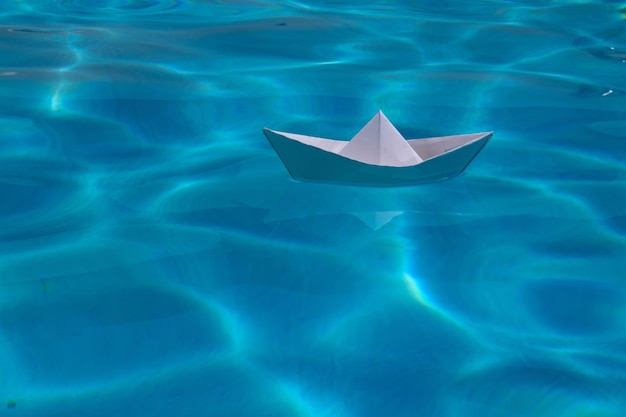 Kreuzfahrtschiff aus Papier, Kunstdruckpapier, das auf der Meeresoberfläche wegsegelt, Wasserhintergrund, Origami-Spielzeugschiff als a