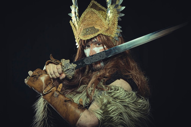 Krieg, Wikinger, skandinavischer Krieger mit Helm und Kriegsmalereien, trägt ein Schwert und einen Umhang aus Tierhaut