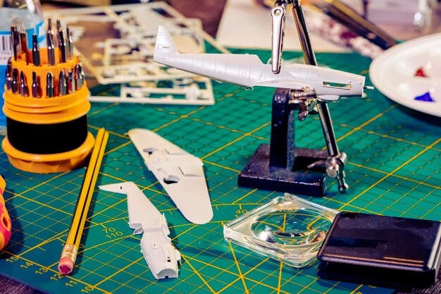 Kriegsflugzeugmodellbau oder Bauhandwerk auf Tisch mit verschiedenen Materialien