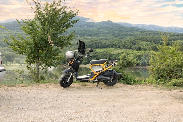 Krim Ukraine 23. Juli 2021 Ein Motorrad ein gelber Roller vor dem Hintergrund eines Sonnenuntergangs in den Krimbergen und einem See Lifestyle