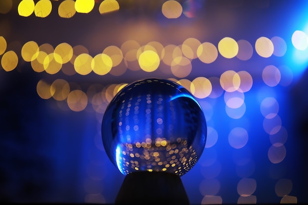 Kristallkugel auf dem Boden mit Bokeh, Lichter dahinter. Glaskugel mit buntem Bokeh-Licht, Neujahrsfeierkonzept.