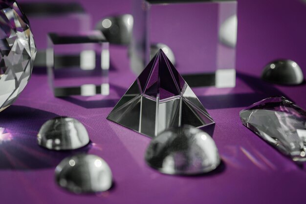 Foto kristallprisma, das licht brecht, magische kristalle und pyramiden, kugel und würfel auf lila hintergrund