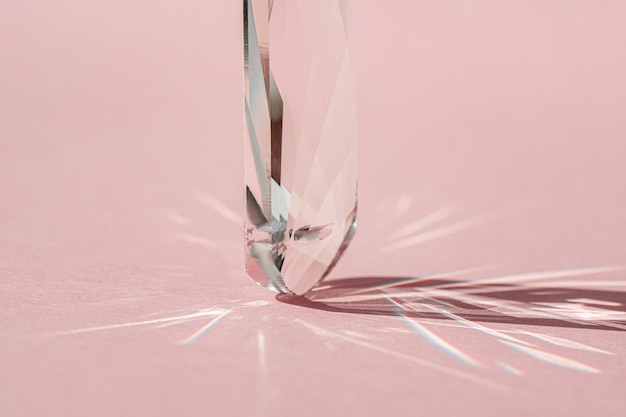 Kristallprisma mit Lichtbeugung von Spektralfarben und Reflexion mit trendigem Licht und harten Schatten auf rosa Hintergrund Lichtspektrum, das durch Glasprisma-Banner reflektiert wird
