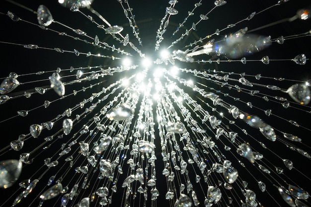 Kristallsteine baumeln und glitzern auf schwarzem Hintergrund glänzender Kristallkronleuchter