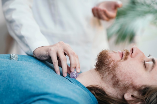 Kristalltherapie mit jungem Mann, der auf Massagetisch liegt