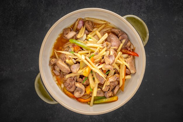 Kruang Nai Gai Pad King, comida tailandesa, despojos de pollo salteados, variedad de carnes, desplume o vísceras con jengibre en un tazón de cerámica sobre fondo de textura de tono oscuro, vista superior