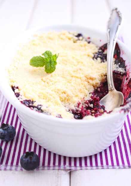 Krümel mit Blaubeere, Heidelbeere in der weißen Platte auf einem weißen Hintergrund.