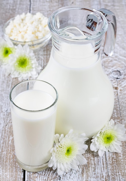 Krug und Glas Milch auf altem Holzbrett