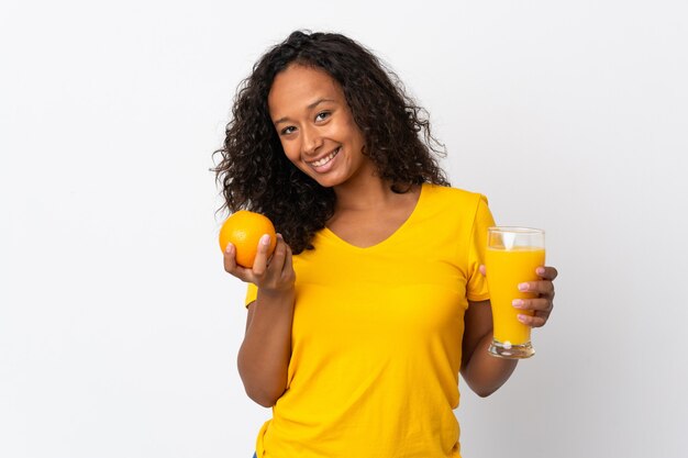 Kubanisches Mädchen des Teenagers lokalisiert auf weißem Hintergrund, der eine Orange und einen Orangensaft hält