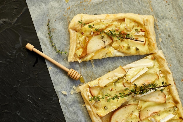 Kuchen gebacken in Blätterteig mit Gorgonzola-Käse und Birnen auf schwarzem Tisch