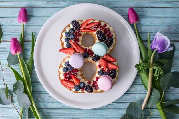 Foto kuchen in form von nummer 8, dekoriert mit beeren und blumentulpen