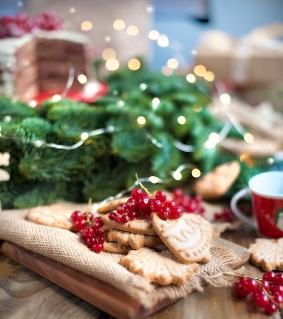 Kuchen mit Beeren und Keksen, Geschenke, in der Nähe eines Weihnachtsbaumes auf einem Dorftisch