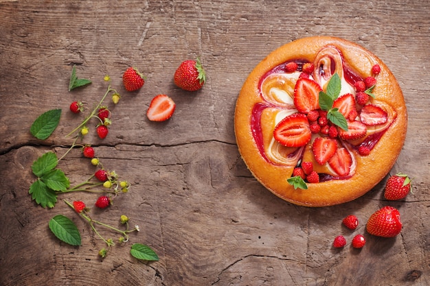 Kuchen mit Erdbeere auf hölzernem Hintergrund