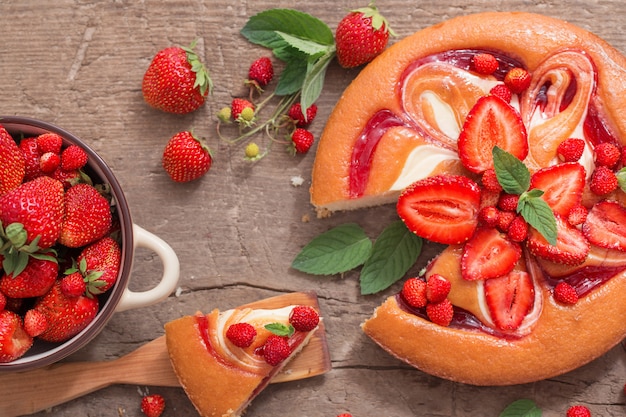 Kuchen mit Erdbeere auf hölzernem Hintergrund