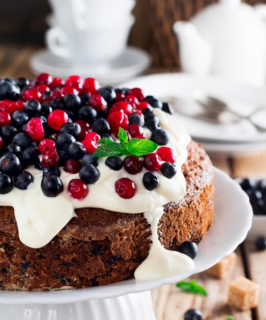 Kuchen mit frischen Beeren und Sahne auf altem Holzhintergrund. Selektiver Fokus.