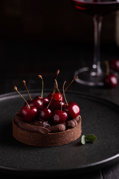 Kuchen mit Kirsch- und Schokoladencreme auf einem schwarzen Teller