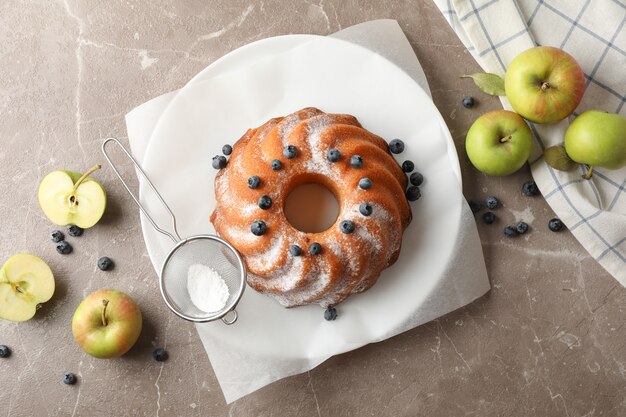 Kuchen mit Puderzucker, Heidelbeere und Äpfeln auf grauem Hintergrund