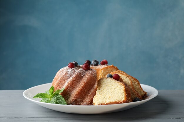 Kuchen mit Puderzucker und Beeren auf hölzernem Hintergrund