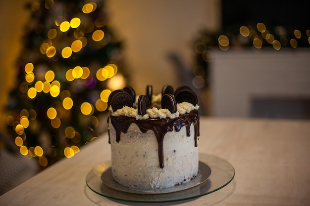 Kuchen mit schwarzen Keksen und mit defokussiertem Weihnachtsbaumhintergrund