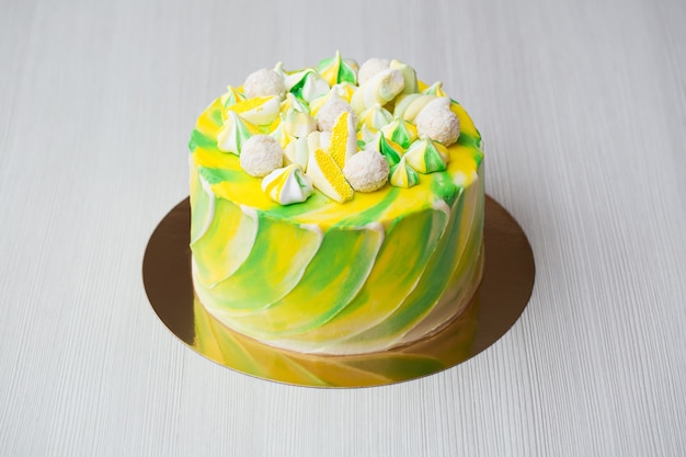 Kuchenaquarellmalerei der gelben und grünen Farbe mit einem Baiser, Süßigkeiten und Marshmallows