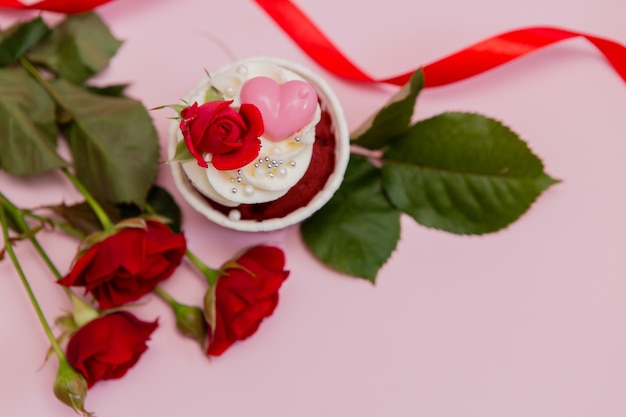 Kuchenrosen und -herzen auf einem Rosa. Schokoladenkleine kuchen verziert mit Sahnerose