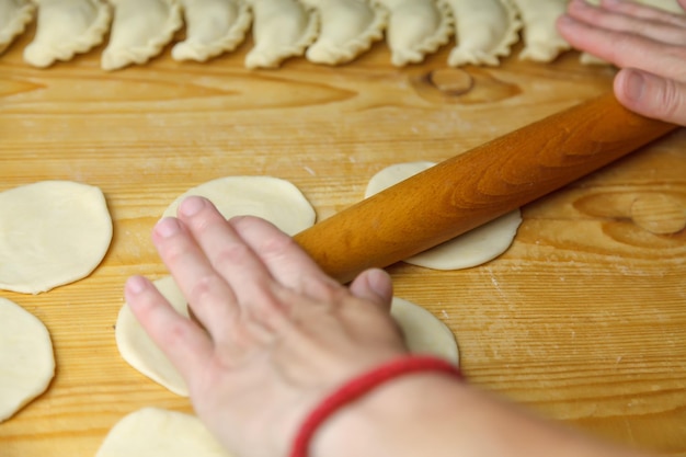 Kuchenteig mit einem hölzernen Nudelholz ausrollen