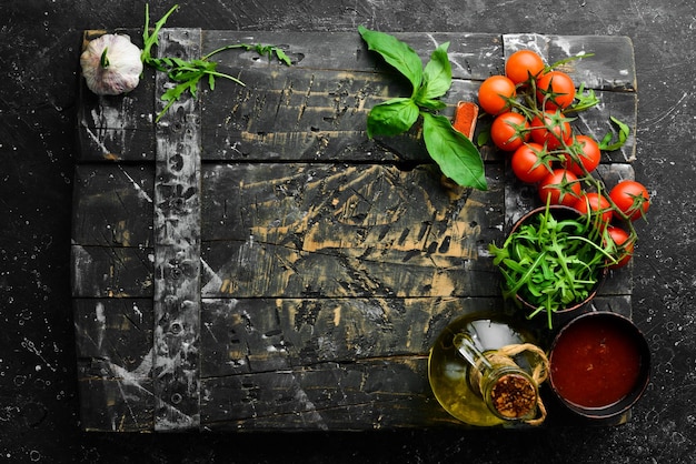 Küche Kochen Hintergrund Kirschtomaten Zwiebeln Gewürze und Kräuter auf schwarzem Hintergrund