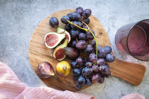 Küchenbrett aus Holz mit frischen Feigen und Trauben