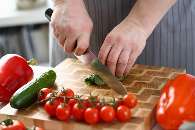 Küchenchef bereitet Salat aus Spinatgurken und Tomaten in der Küche zu
