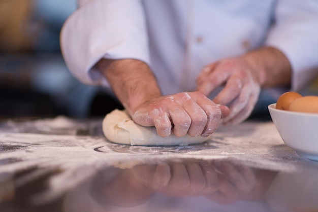 Küchenchef Hände bereiten Teig für Pizza auf mit Mehl bestreuten Tisch Nahaufnahme