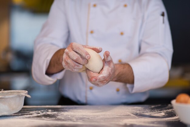 Küchenchef Hände bereiten Teig für Pizza auf mit Mehl bestreuten Tisch Nahaufnahme