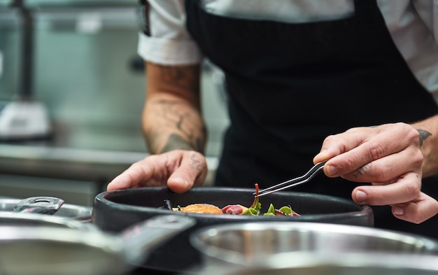 Küchenchef Hände garnieren Pasta Carbonara in einer Restaurantküche