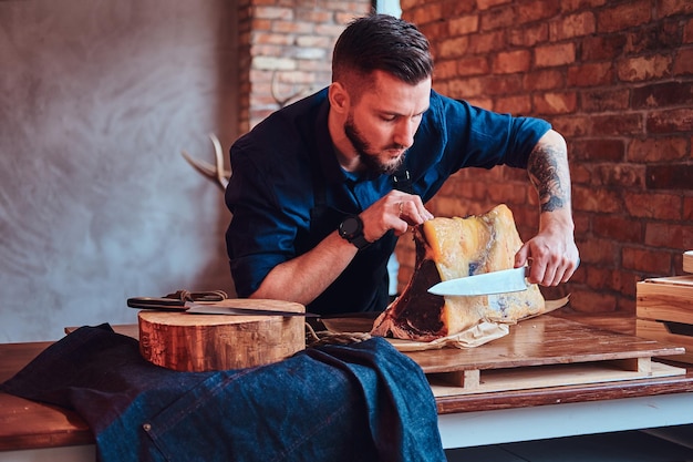 Foto küchenchef schneidet exklusives jerky-fleisch auf einem tisch in einer küche mit loft-interieur.